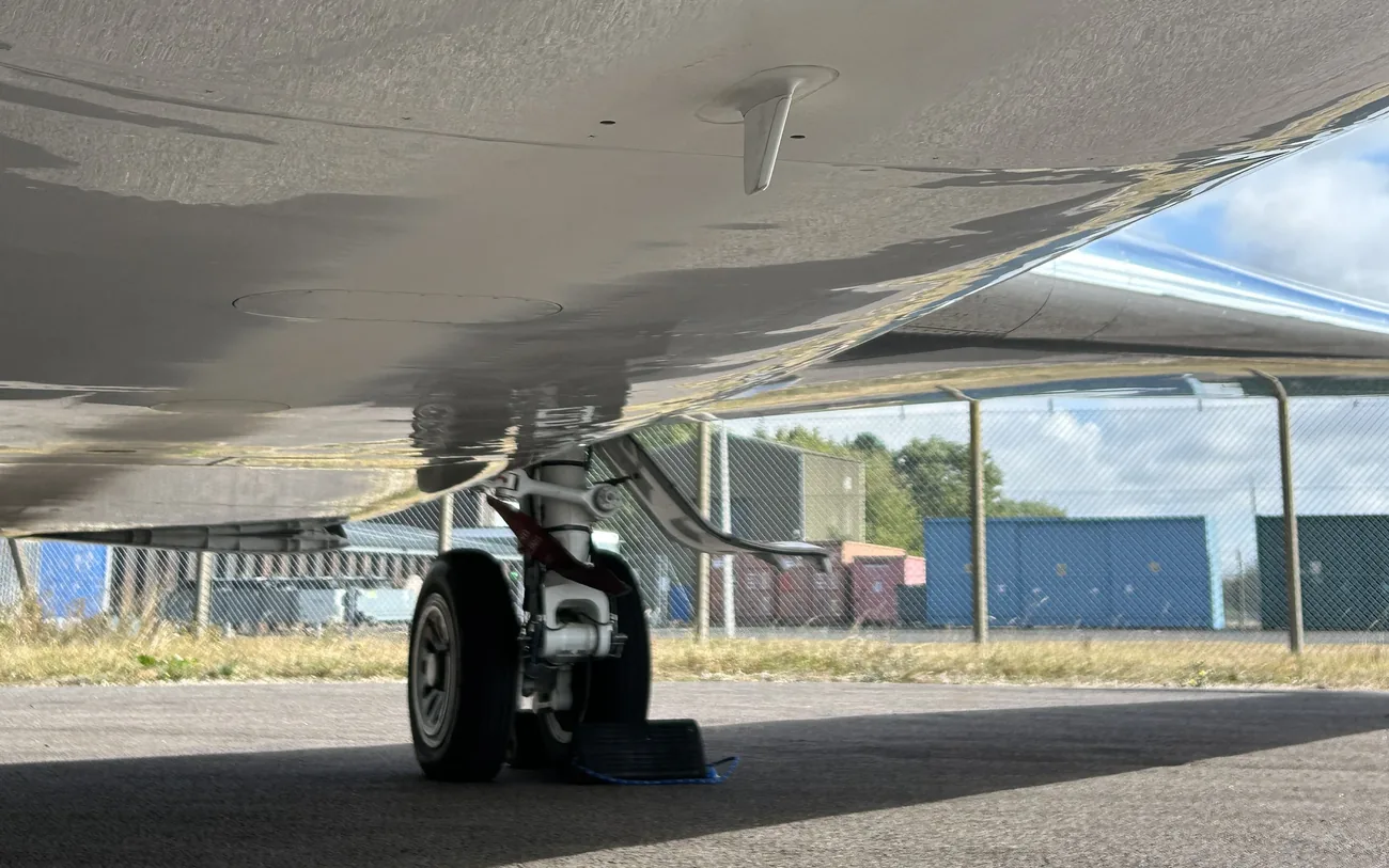 Private jet belly and nose gear before cleaning, with dull, filmed-over paintwork